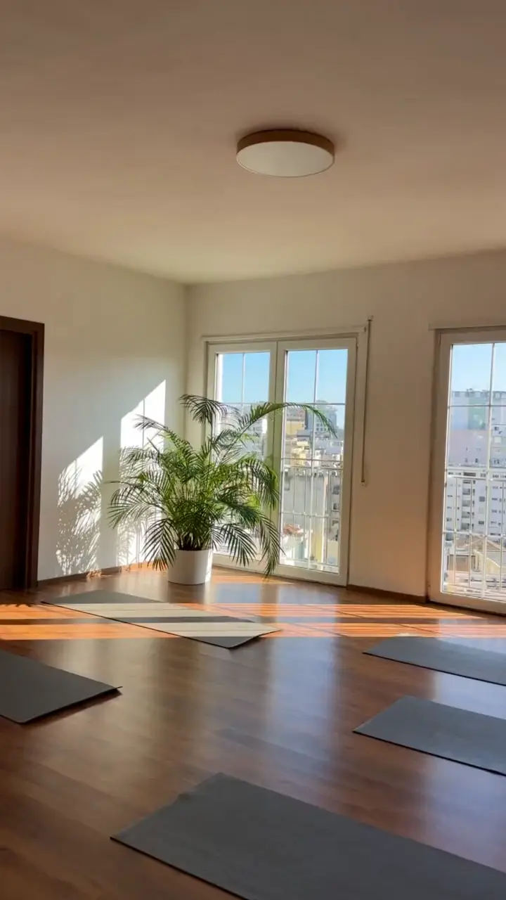Sunlit movement room at Sundara Studio with mats, palms and tall windows